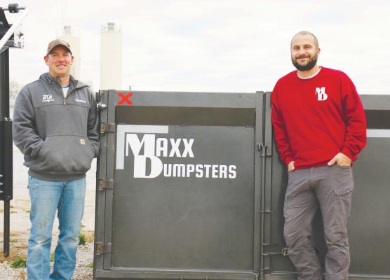 MAXX DUMPSTERS owners Spencer Synowski and Tyler Solko stand in front of one of the roll-off dumpsters belonging to their new business venture outside the office of STS Construction last week. The two also co-own STS. Photo by Michael Rother