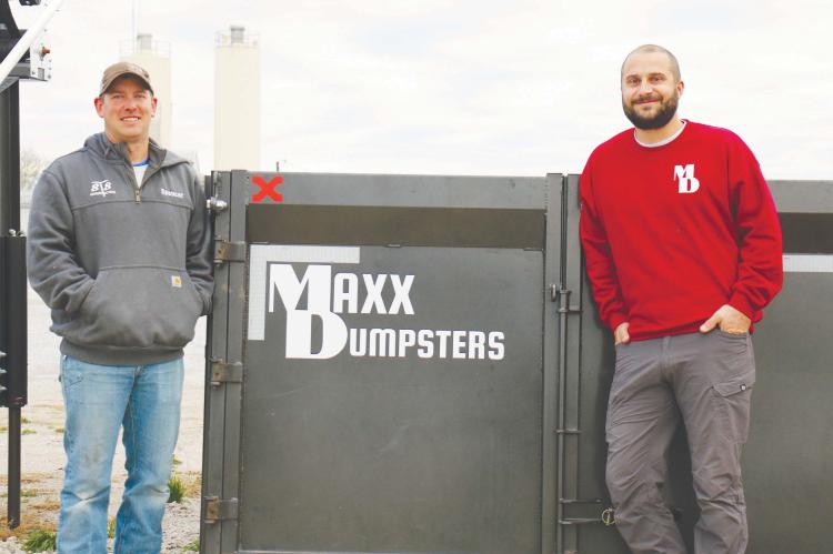MAXX DUMPSTERS owners Spencer Synowski and Tyler Solko stand in front of one of the roll-off dumpsters belonging to their new business venture outside the office of STS Construction last week. The two also co-own STS. Photo by Michael Rother