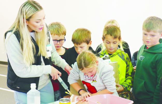 ST PAUL FOURTH GRADERS learn the fundamentals of applying pressure to a wound from Registered Nurse Emily Almond at the Stop the Bleed station at last Tuesday’s On Track to Wellness event at Howard County Medical Center. Photo by Michael Rother