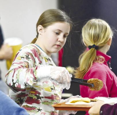 HOWARD COUNTY 4-H Member Shyann Borwege helps man the serving line during Sunday’s 4-H Pancake Feed at the Howard County Fairgrounds. Photo by Michael Happ