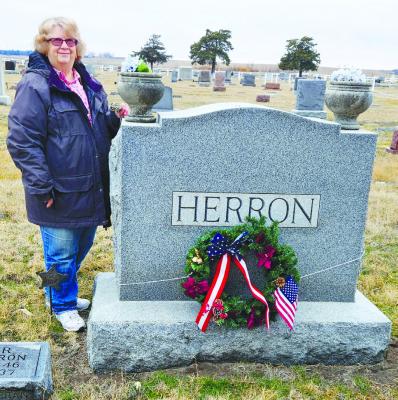 AMERICAN LEGION AUXILIARY President Char Schmid stands next to the graves of Leander Herron and his wife, Emma, on December 15th. Courtesy Photo