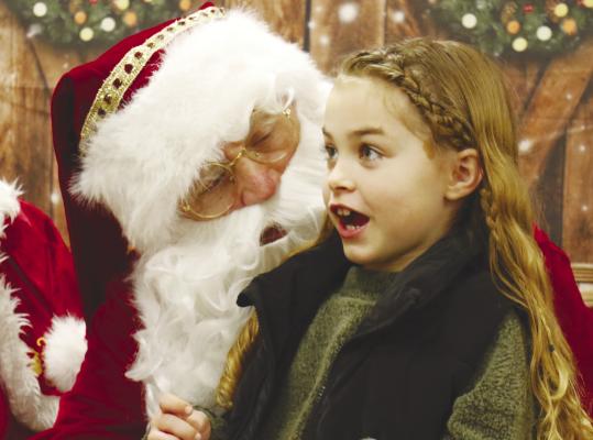 SANTA CLAUS made a stop in St. Paul over the weekend, with Mr. and Mrs. Claus participating in the St. Paul Area Chamber of Commerce’s annual Jingle Around Town event on Saturday. Above, Isabella Harders enjoyed ticking items off her Christmas list. Photo by Michael Rother