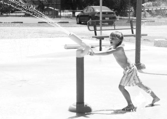 OWEN ANDERSON mans the water cannon at the Wolbach Splash Pad and Playground grand opening ribbon cutting event last Thursday. The event, which featured speeches from Matt Steenson and representatives of the offices of United States Senator Deb Fischer, Congressman Adrian Smith, and others, marked the culmination of an eight-year-long project. Photo by Michael Rother