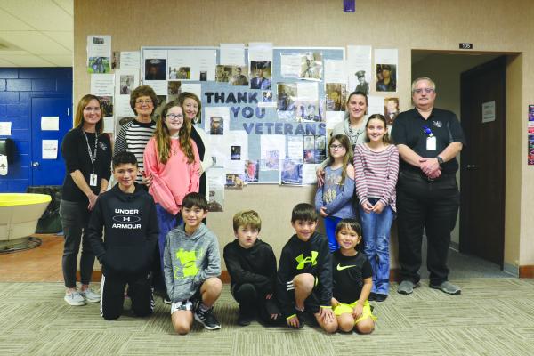 SEVERAL STAFF AND STUDENTS of St. Libory Public Schools had relatives featured on the school’s Wall of Valor, which honors area veterans. Among them, left to right, are, back row, Jenny Manivong, Carolyn Tyma, Amber Dizmang, Amanda Hodges, and Kevin Snyder; middle row, Madison Dizmang, Gabby Hodges, and Maggie Hodges; and, front row, Keldrick Manivong, Ashton Manivong, Ivan Dizmang, Dillon Manivong, and Brantley Manivong. (Michael Rother)