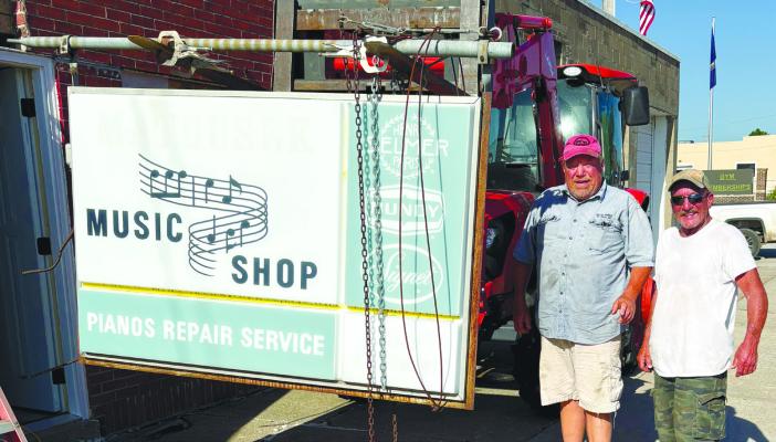 JEFF CHRISTENSEN AND BRIAN YEOMANS are pictured next to the Matousek Music Shop sign, which they recently donated to the Howard County Historical Society. Courtesy Photo