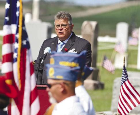 MEMORIAL DAY was observed at Elmwood Cemetery in St. Paul on Monday, with services being conducted by the Carl Mogensen American Legion Post 119, American Legion Auxiliary Unit 119, and the Sons of the American Legion. Above, George K. Szatko, Jr., a retired member of the United States Marine Corps, delivers the Memorial address. Photo by Michael Rother
