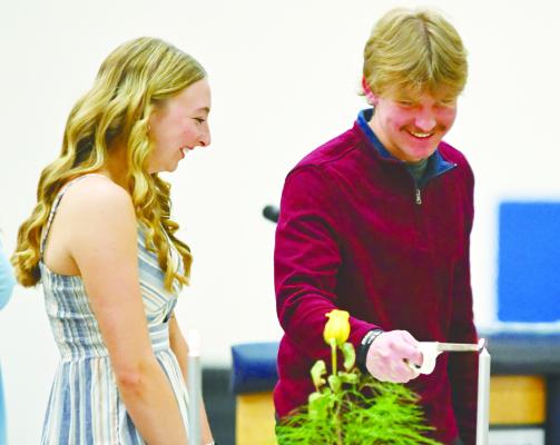 ILLUSTRATING the National Honor Society’s pillar of service, Historian Brecken Kavan lent Secretary Charlee Wegner a hand by lighting her candle during last Tuesday’s National Honor Society induction ceremony at St. Paul High School. Photos by Michael Happ