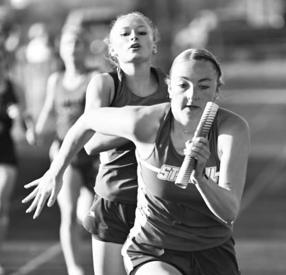 CHARLEE WEGNER jumpstarts the second leg of St. Paul’s 1600-meter relay on Thursday, having taken the baton from Kamden Sack. The St. Paul girls set a new school record in that race, completing the relay in 4:10.08. Photos by Michael Happ