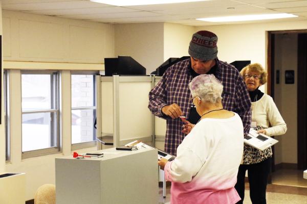 POLL WORKER Jackie Mayberry hands Todd Wojtalewicz a sticker after Wojtalewicz cast his ballot at the Howard County Courthouse last Tuesday morning. The polling site was a popular place to be shortly after the polls opened. (Courtney Leth)