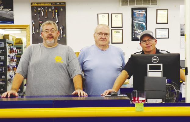 GAYLORD BOILESEN of Ord (center) is pictured with employees Bryan Coxbill (left) and Mike Thompson (right) inside the NAPA auto parts store in St. Paul. Boilesen sold the St. Paul store, along with his store in Ord, last month. Photo by Michael Rother