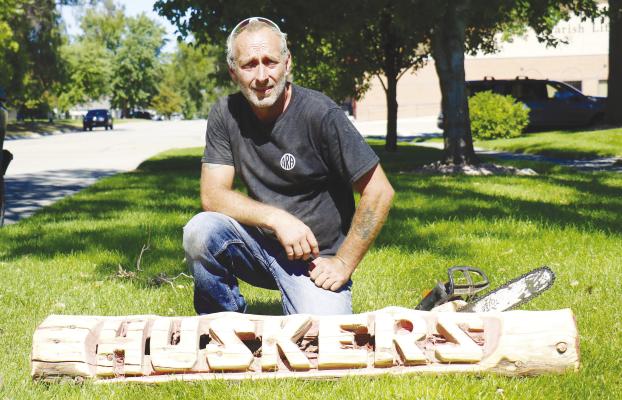 JIMMY SMITH is pictured with one of the Husker signs he has carved. Smith has been using a chainsaw to make carved pieces for the past four years, selling them on social media and through other outlets. Photos by Michael Rother