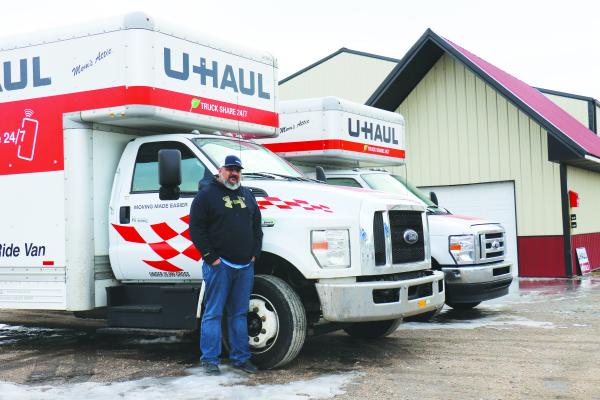 JARED RICE, general manager of U-Betcha Auto in St. Paul, stands next to two of the U-Haul trucks that are available for rent from the St. Paul car dealership. U-Betcha began its new offering as a U-Haul satellite rental location on January 13th. (Michael Rother)