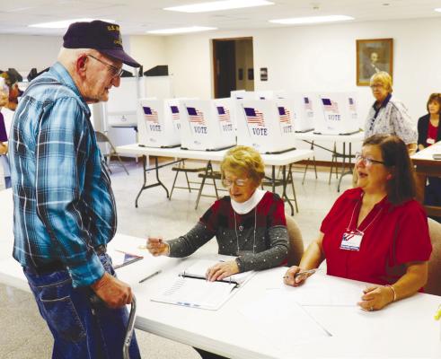 POLL WORKERS Velda Peters and Linda Bogus greet Carl Vang as he prepares to vote inside the Howard County Courthouse on Tuesday.