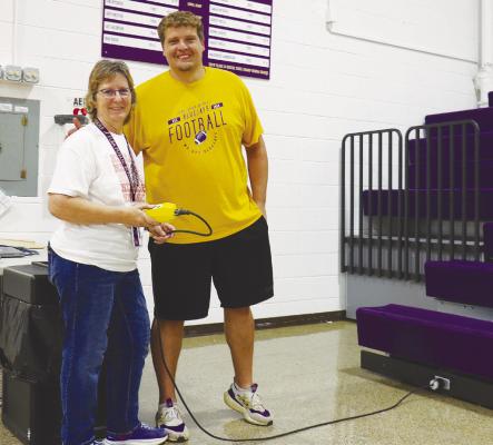 ELBA Head Custodian Tamy Morrow and Athletic Director Logan Simmerman are pictured with the new retractable bleachers, which move at a button press. Photo by Michael Rother