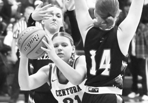 KASSIDY HURT attempts to thread her way past a pair of Arcadia/Loup City defenders on her way to the basket during Saturday’s conference tournament consolation game. Photo by Michael Happ