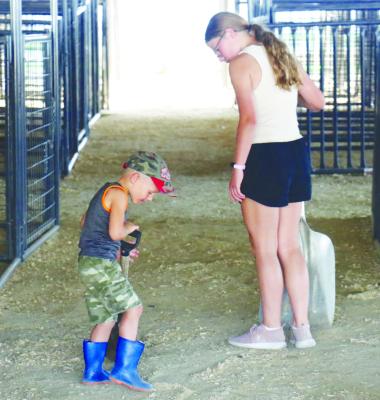 TROY DUBAS AND CLAIRE DUBAS work to clean out one of the livestock barns during Monday night’s clean-up event at the Howard County Fairgrounds. Photo by Michael Rother