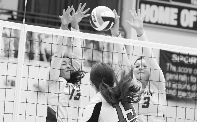 ZAYA LEWIS AND GRACIE KELLEY attempt to block a shot from Doniphan-Trumbull’s Baylee Larson during last Thursday night’s match between the Wildcats and the Cardinals. Photos by Michael Happ