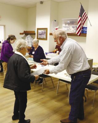 THE 2024 GENERAL ELECTION brought out big crowds to precincts across Howard County on Tuesday. Above, Elizabeth Keep turns in her ballot and receives an “I Voted” sticker from poll worker Dennis Sperling at the St. Paul Ward 1 poling place inside the St. Paul Library. Photo by Michael Rother