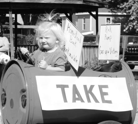 BRODIE SWETT enjoys a sucker while chugging along in the Homstead Bank cab of the multi-business train during Friday’s homecoming parade.