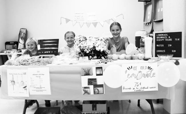 ADELAIDE’S ART SHOP set up shop in the Wolbach Community Center for Junk Jaunt, selling custom earrings, goat’s milk soap, confectionaries, and lemonade to raise money for the Childhood Cancer Foundation, among other items. Pictured manning the shop on Sunday are sisters Pearl, Ruby, and Adelaide Bernt. Photo by Michael Rother