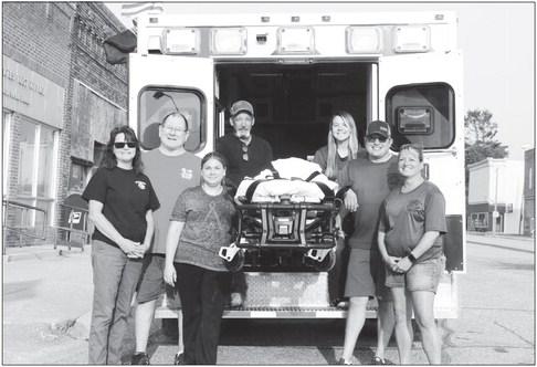 THE WOLBACH VOLUNTEER FIRE DEPARTMENT AND EMTS recently purchased a new ambulance cot and fastener system. Firefighters and EMTs pictured with the new cot last week include Ann Wadsworth, Captain Rick Brown, Training Officer Beckie Brown, Ron Tubbs, Kortney Daniels, Patrick Killinger, and Trish Nelson. Photos by Michael Rother