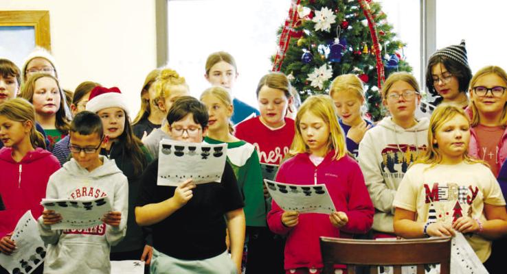 ST. PAUL ELEMENTARY SCHOOL students helped spread some holiday cheer in downtown St. Paul last Friday, the students’ final day of the fall term. Students caroled at three locations last week: the Howard County Courthouse, the office of the St. Paul Area Chamber of Commerce, and the St. Paul Senior Center. Above, fifth grade students are pictured singing carols to visitors of the senior center. Photo by Michael Rother