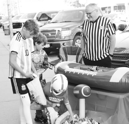 TODD PETERS with Peters Funeral Home looks on as kids pick up candy from the funeral home’s booth during the Howard County Medical Center’s annual Jack-O-Lantern Jog on Saturday morning in downtown St. Paul. Photo by Michael Rother