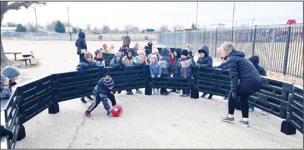 KINDERGARTEN students at St. Paul Elementary School are pictured playing gaga ball with Paraprofessional Mrs. Courtney Griebel at recess. The school’s two gaga ball courts, which have been “unbelievably popular,” were purchased and installed late last year. (Courtesy Photo)