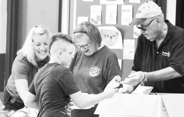 THE ROTARY CLUB OF ST. PAUL helped feed hungry students and their families last Tuesday night during St. Paul Public Schools’s annual Back to School Open House. Lending a hand dishing up the hot dog meal were Katie Mathews, Loraine Lawler, and Robin Elstermeier. Photo by Michael Happ