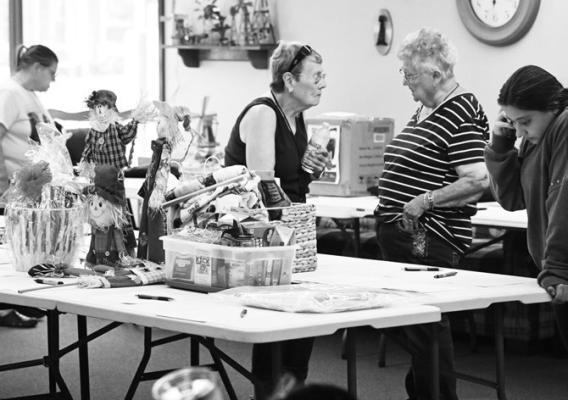 THOSE WHO ATTENDED the Dugout BBQ Challenge in St. Paul on Saturday evening also had the chance to win raffle prizes that were on display inside the St. Paul Senior Center. Above, attendees look over the items available to win during last week’s event. Photo by Michael Happ