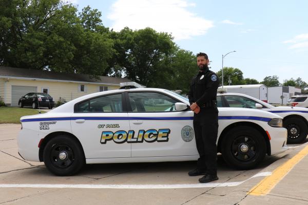 OFFICER CHRIS GROOMS, the St. Paul Police Department’s newest certified officer, is pictured next to one of the municipal police department’s cruisers on Monday afternoon. (Michael Rother)