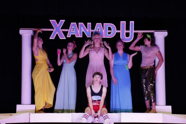 SONNY MALONE (Boston Wood) contemplates his future as an artist and roller disco aficionado while several muses, Clio (Morgan Rosander) being chief among them (center back), look on. Clio’s siblings, behind her from left to right, are Terpischore (Alexis Johnson), Euterpe (Emma Corman), Urania (Kennady Holley), and Thalia (Zaden Wolf). (Michael Rother)