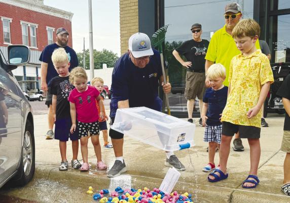 GREYSON KNAPP, ClaraLynn Peters, Hudson Knapp, and Dean and Elliot Egger watch as Tom Powell lets the ducks loose as a part of Friday night’s duck races.