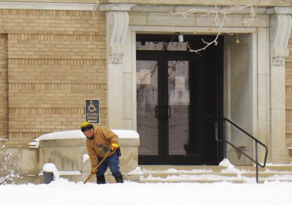 HOWARD COUNTY CUSTODIAN Pat Koperski works to clear the sidewalks at the Howard County Courthouse last Thursday. The courthouse’s operations, like those of many businesses and governments, were impacted by last week’s snow storm. (Michael Rother)
