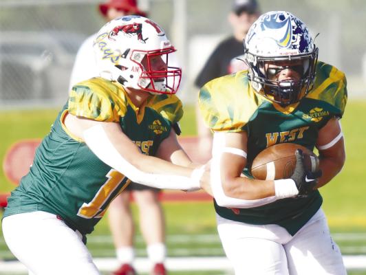 CENTRAL VALLEY’S GRADY KELLY takes a handoff from West Quarterback Ethan Shaw of Sandy Creek During last week’s all-star game at Hastings College. The West team lost to the East team 14-8. Photos by Jordan Coslor
