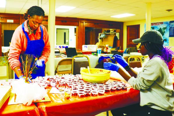 DR. REVEREND SUSAN MURITHI, pastor of the United Methodist Church in St. Paul, and her daughter, Faith, help to prepare containers of cranberry sauce for delivery at the First Presbyterian Church on Wednesday afternoon. Photos by Michael Rother