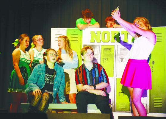 CADY HERON (EMMA CORMAN) gets a little too into her “Plastic” persona as she checks an SMS on her newfanlged Motorola “peanut” phone during the November 13th staging of Mean Girls at the Central Valley One Act Festival in Scotia. Sitting down, her friends Janis (Laretta Davis) and Damian (Ethan Lobner) look on with concern. Photo by Michael Rother