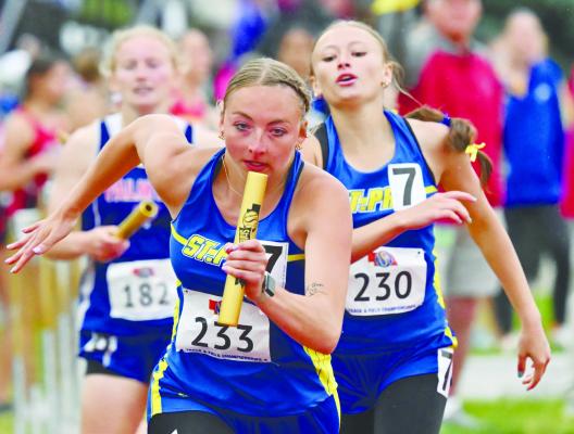 ST. PAUL’S CHARLEE WEGNER sprints away from the first exchange of the girls’ 1600-meter relay on Friday after taking the baton from Kamden Sack. Wegner earned her first-ever state medal in that event, with the relay team placing fifth in 4:07.57, which was also good enough for a school record. Photo by Michael Happ