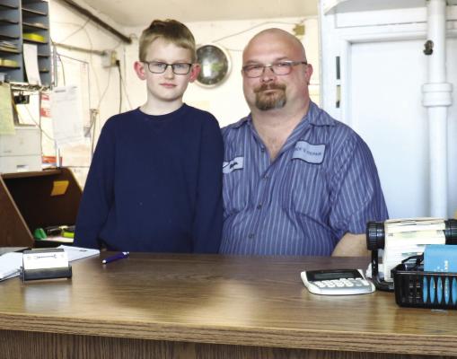 KEVIN WOITASZEWSKI, the new owner of Dick's Repair, is pictured inside the repair shop's office on Seventh Street. Woitaszewski is pictured alongside his eight-year-old son, Evin. (Michael Rother)