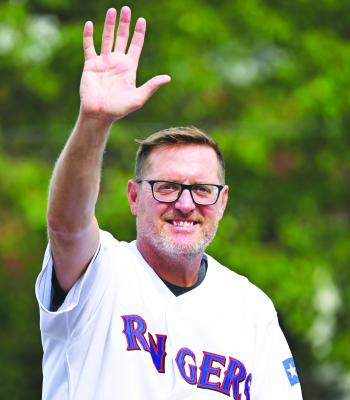 TRAVIS HUGHES, the grand marshal of the 2025 Grover Cleveland Alexander Days Parade, waves to the crowd gathered on Howard Avenue on Saturday.