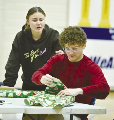 INTERACT CLUB Member Norah Paulsen looks on as Jack Thede works to wrap a present during Sunday’s second afternoon of the St. Paul Rotary Interact Club’s gift wrapping fundraiser at St. Paul Public Schools. Photo by Michael Happ