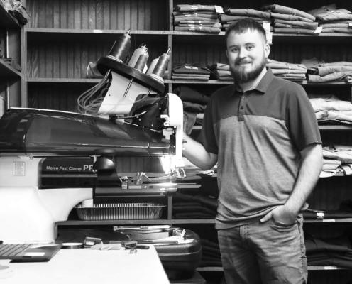 DYLAN WOODGATE, owner of Bryan Jensen Clothing in St. Paul, is pictured next to the store’s Bernina embroidery machine, which was moved to Bryan Jensen’s Howard Avenue location after the store acquired HD Graphix last year. (Michael Rother)