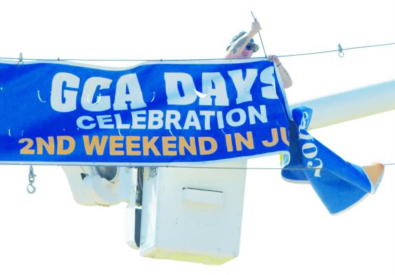 JAROD GREENOUGH with the City of St. Paul Electrical Department hangs the GCA Days banner over Howard Avenue on Tuesday morning. Photo by Michael Happ
