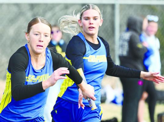 MAKING THE FINAL EXCHANGE in the girls’ 400-meter relay at the Arcadia/Loup City Invite are St. Paul runners Katie Oakley and Piepyr Klinginsmith. The Wildcats placed second in the shortest relay race behind the girls from Ord. Photo by Michael Happ