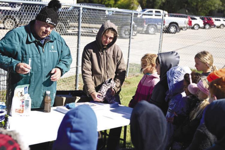 ST. PAUL VETERINARIAN DR. ADRIAN ANDERSON, with the help of Ki Haggerty, teaches St. Paul Elementary students about how to safely work with small animals during Ag Safety Day at St. Paul Public Schools last week. Photo by Michael Happ