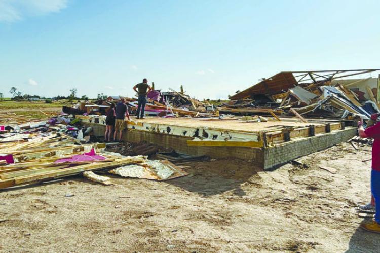 INDIVIDUALS SURVEY DAMAGE to a home at Denton Road and 7th Avenue earlier this week. A tornado caused damage to four homes in the area and across parts of Howard County on Sunday afternoon. Courtesy Photo