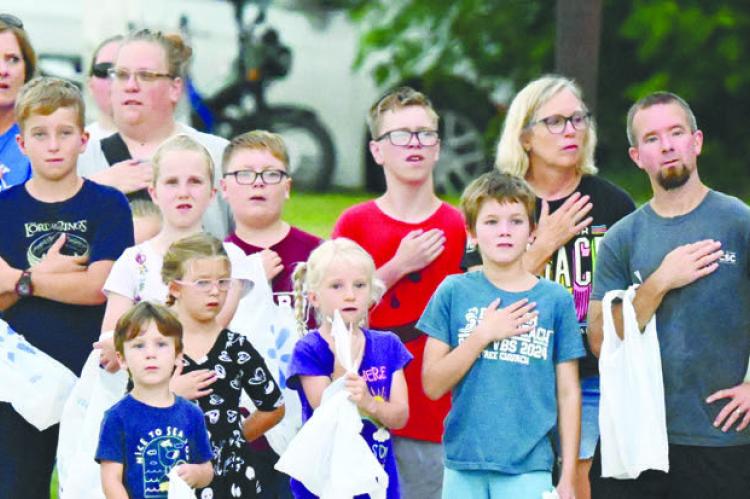 PARADEGOERS gathered along the parade route along Deleware Street in downtown Boelus on Saturday stand at attention for the playing of the national anthem prior to the start of the parade. Photos by Michael Happ