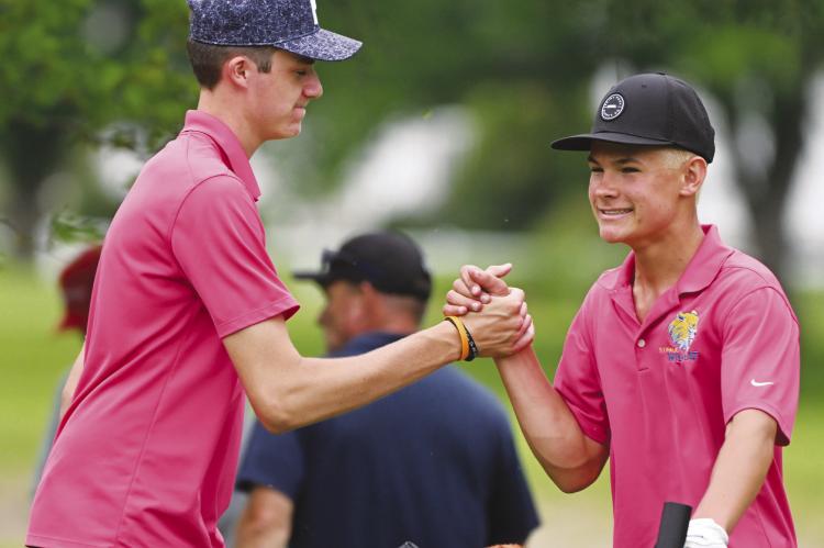 MADDOX QUINN congratulates Casen Kavan after the sophomore sinks a putt on the eighteenth hole of the state championship course on Thursday afternoon in Grand Island.