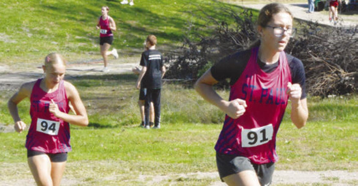 ST. PAUL’S JILLIAN WELLS AND JULIA KLEINSASSER battle up a hill during last week’s LouPlatte Conference Cross Country meet in Ord. Photo by Monte Steele