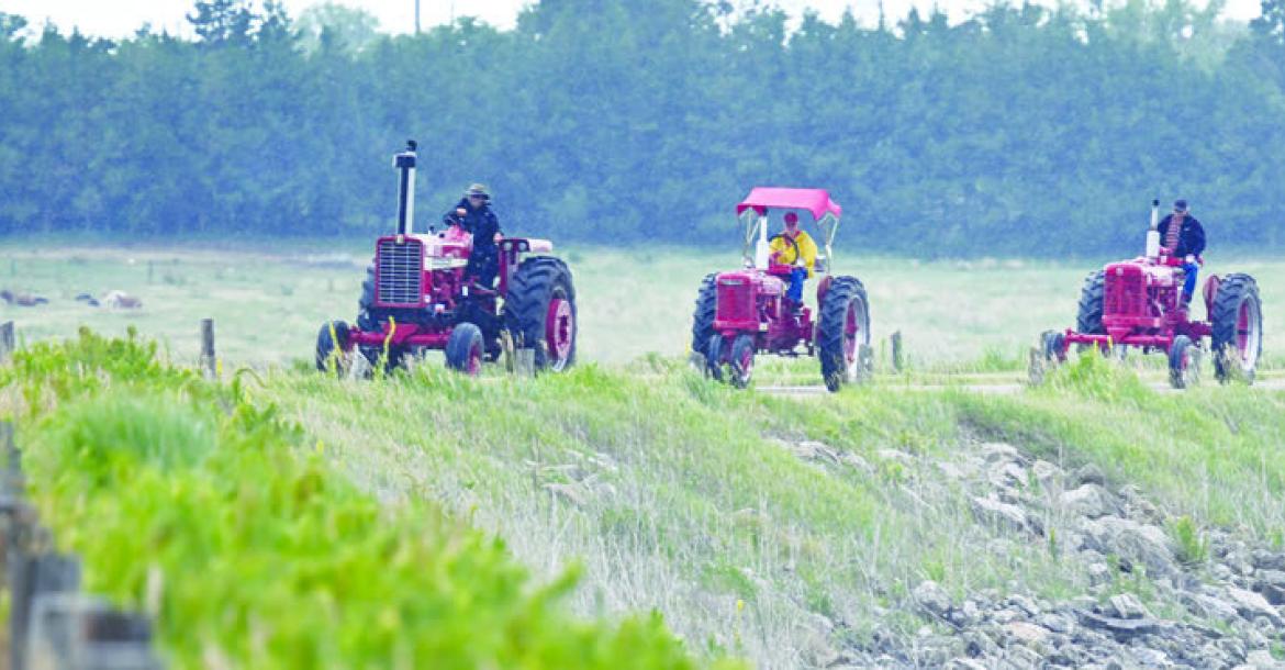 MEMBERS of the Central Nebraska Antique Tractor and Equipment Club make their way across the dam at Sherman Reservoir on Friday morning during the club’s annual tractor drive. Thirty-two tractors and sixty-five people participated in this year’s event. Photo by Michael Happ
